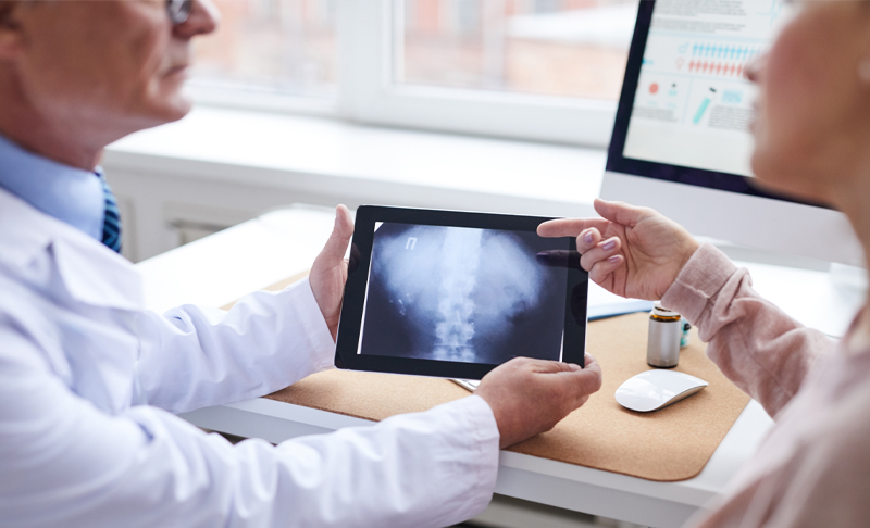 doctor and patient looking at x-ray on tablet